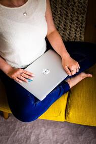 A woman sitting on a couch ready to open a laptop 